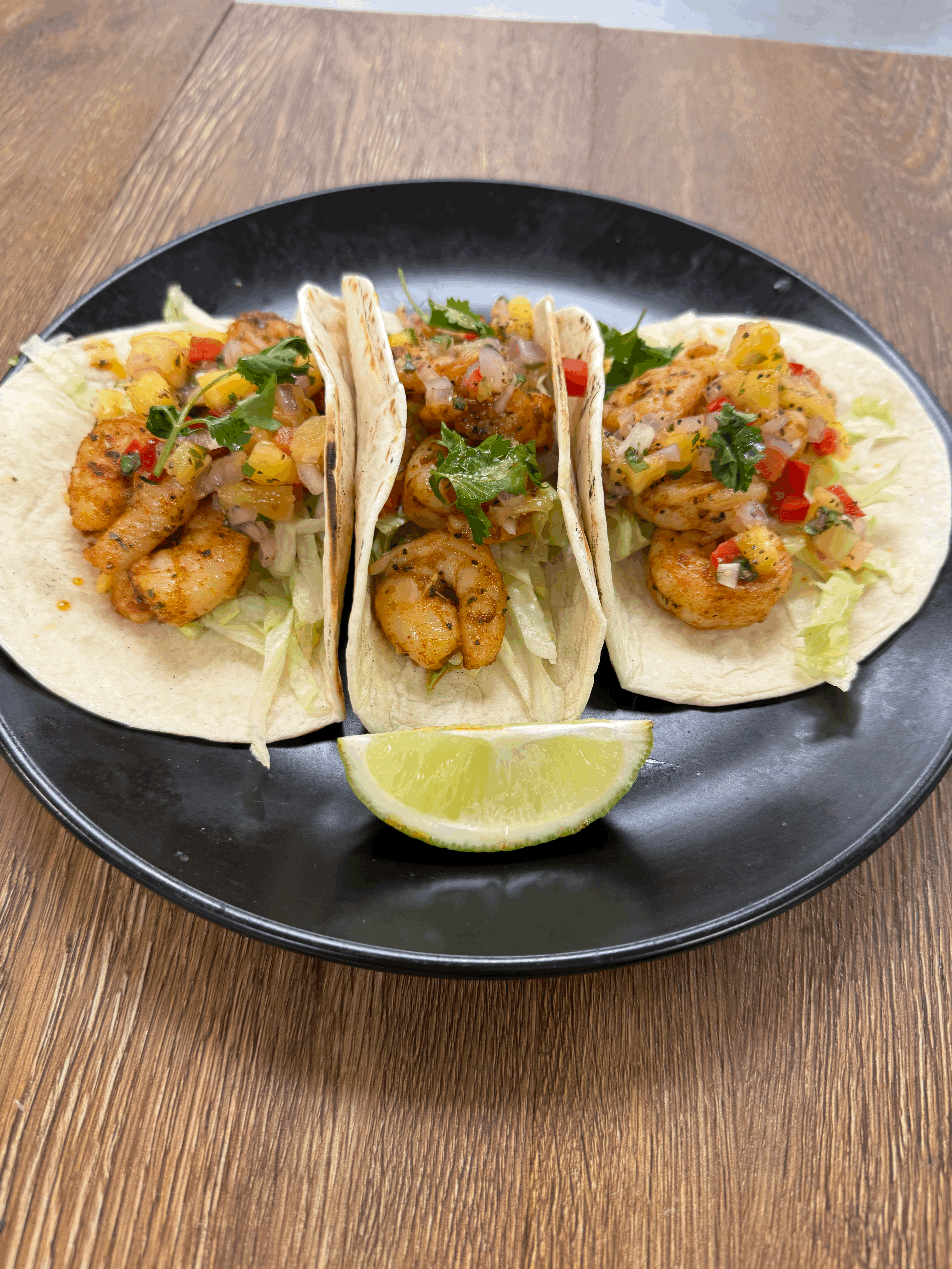 Shrimp Tacos, 3 Grilled flour shells filled with
blackened shrimp, topped with chopped lettuce,
pineapple mango salsa and fresh cilantro. Served
with a lime wedge and a side of sour cream.