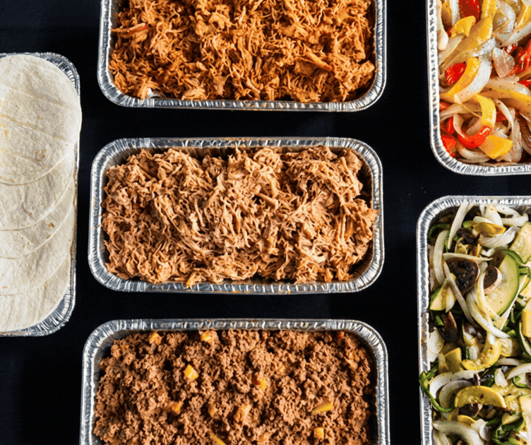 Assorted taco bar ingredients: two pans of shredded meat, one pan of ground meat, one pan of sautéed bell peppers and onions, and one pan of mixed vegetables.