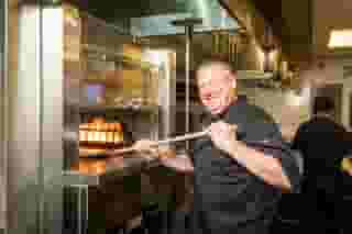 Fred, a chef, putting food into a large oven
