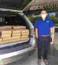 Back of mini-van packed with Urth Caffé lunch boxes with masked nurse getting ready to unload them.