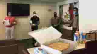 Room inside Beverly Hills City Hall with two officers and two staff member standing against walls. Table in foreground has large Urth Caffé crumb coffee cake, OJ cartons and paper coffee despensers.