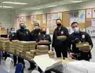 group of six police persons in front of a table full of Urth Lunch Boxes and coffee