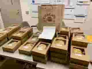 Table full of Urth lunch boxes with one big Urth bag sitting on top in the back.