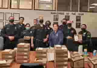 group of many police persons in front of a table full of Urth Lunch Boxes and coffee