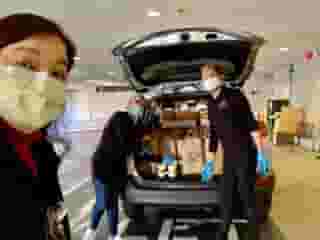 Three nurses unloading back of minivan full of Urth Caffé food bags and lunch boxes.