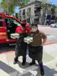 2 Urth Melrose employees holding drinks in from of parked emergency vehicle