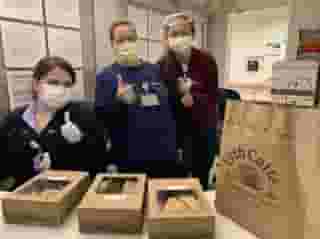 Three nurses with masks giving thumbs up while standing behind Urth lunch boxes and Urth bag.