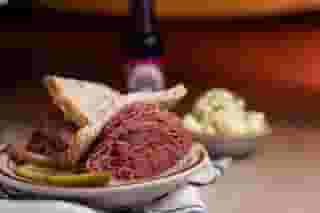corned beef sandwich with potato salad and a soda