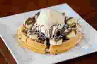 waffle topped with chocolate drizzle, bananas, and creme