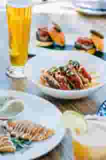 Multiple different menu items plated with a beer