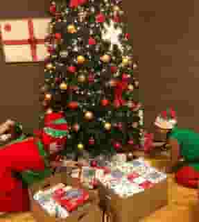 two people placing gifts under a christmas tree