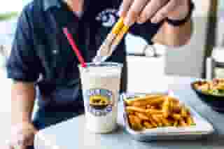 Man dipping moonie's fries into a moonie's shake
