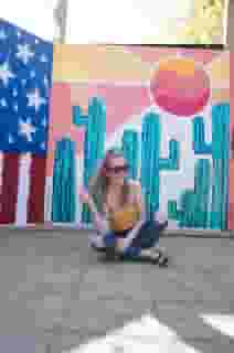 Women sitting in a brightly lit outside area decorated with a variety of murals