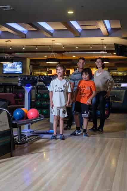 Family posing for a photo while playing a game of bowling