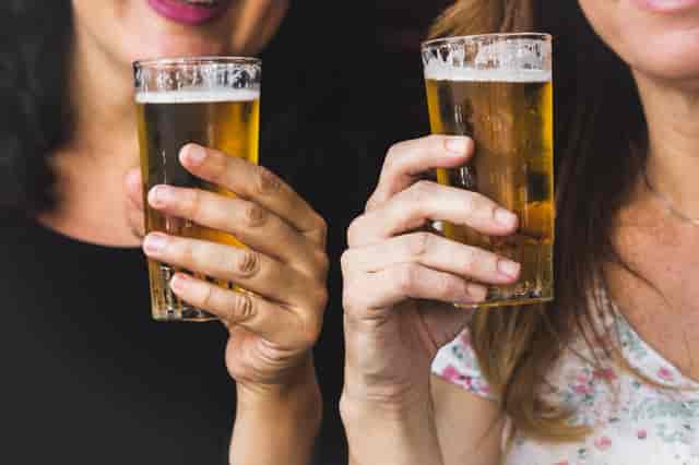 Two women holding up from the tap beers