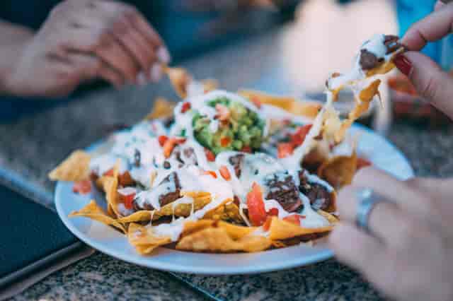 Nachos being pulled apart about to get eaten