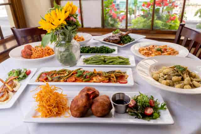 Place setting with a white linen table cloth, fine dishware and a vase of yellow flowers