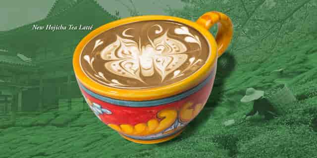 Cup of Hojicha Tea Latté with latté butterfly design with green Japanese tea farm