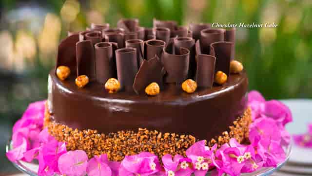 Whole Chocolate Hazelnut Cake with pink flowers around base