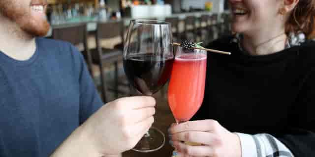 Man and woman drinking wine and cocktails during twilight dinner at table 47