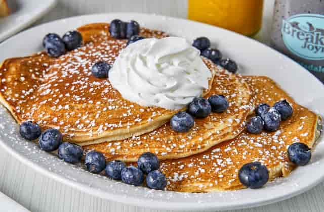 three pancakes topped with blueberries and whipped cream
