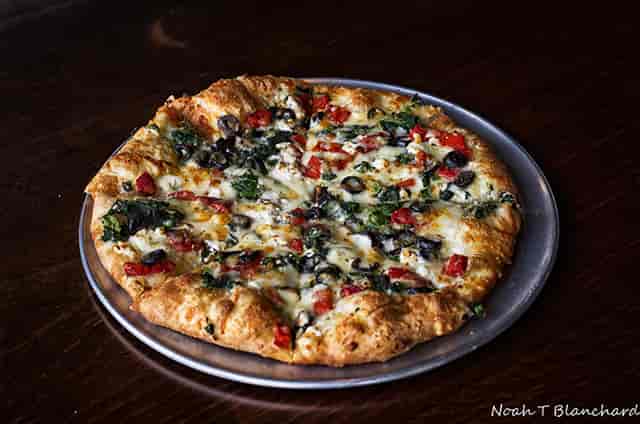 Pizza with olives, tomatoes and spinach