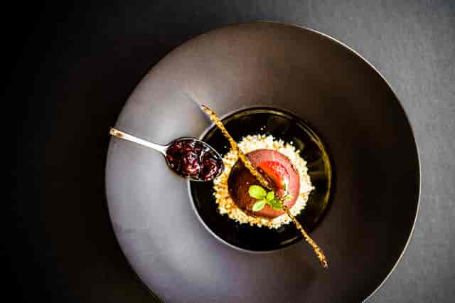 Chocolate Mousse: Delectable chocolate mousse on a bed of crushed cashew nuts served over blue and black berry sauce.