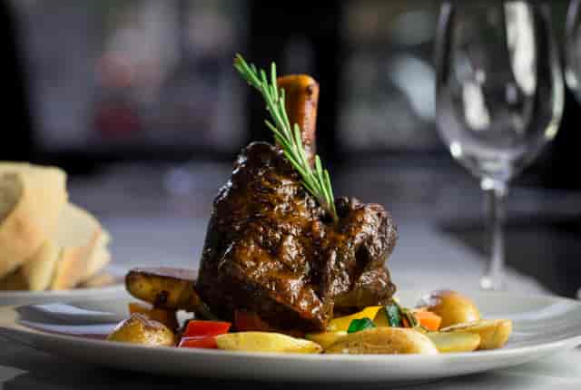 Lamb Shank: Slow braised lamb shank in red wine, garlic and rosemary, served with potatoes and mixed vegetables