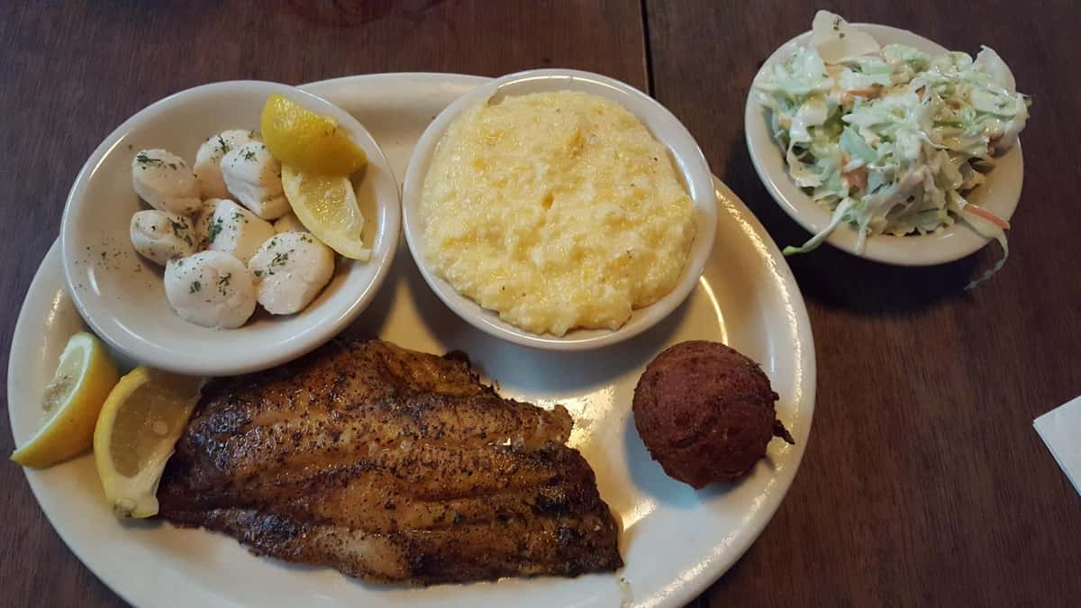 grilled fillet of fish with a side of mac and cheese, hush puppies, and coleslaw