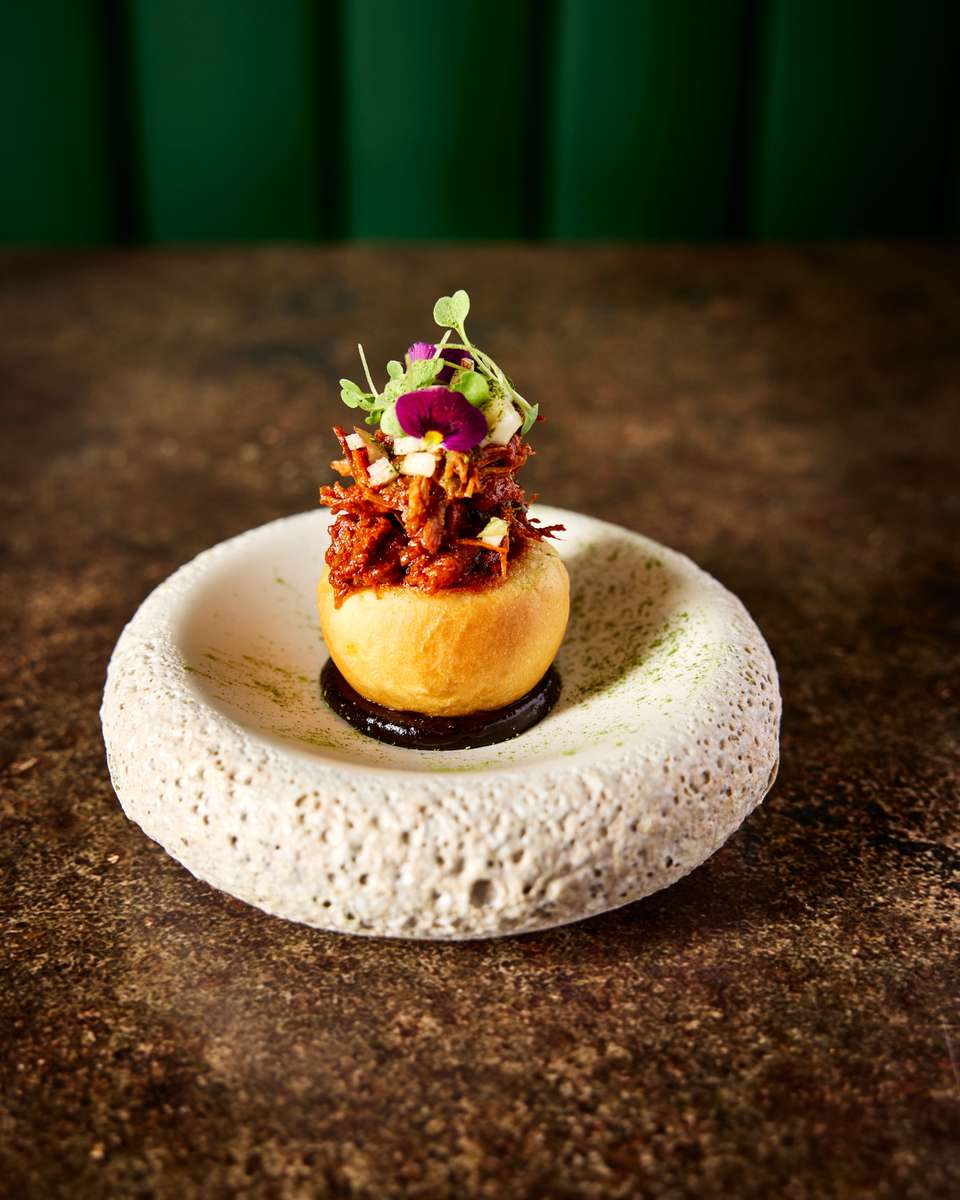 A gourmet dish garnished with microgreens and edible flowers, served on a textured plate, showcasing culinary artistry.