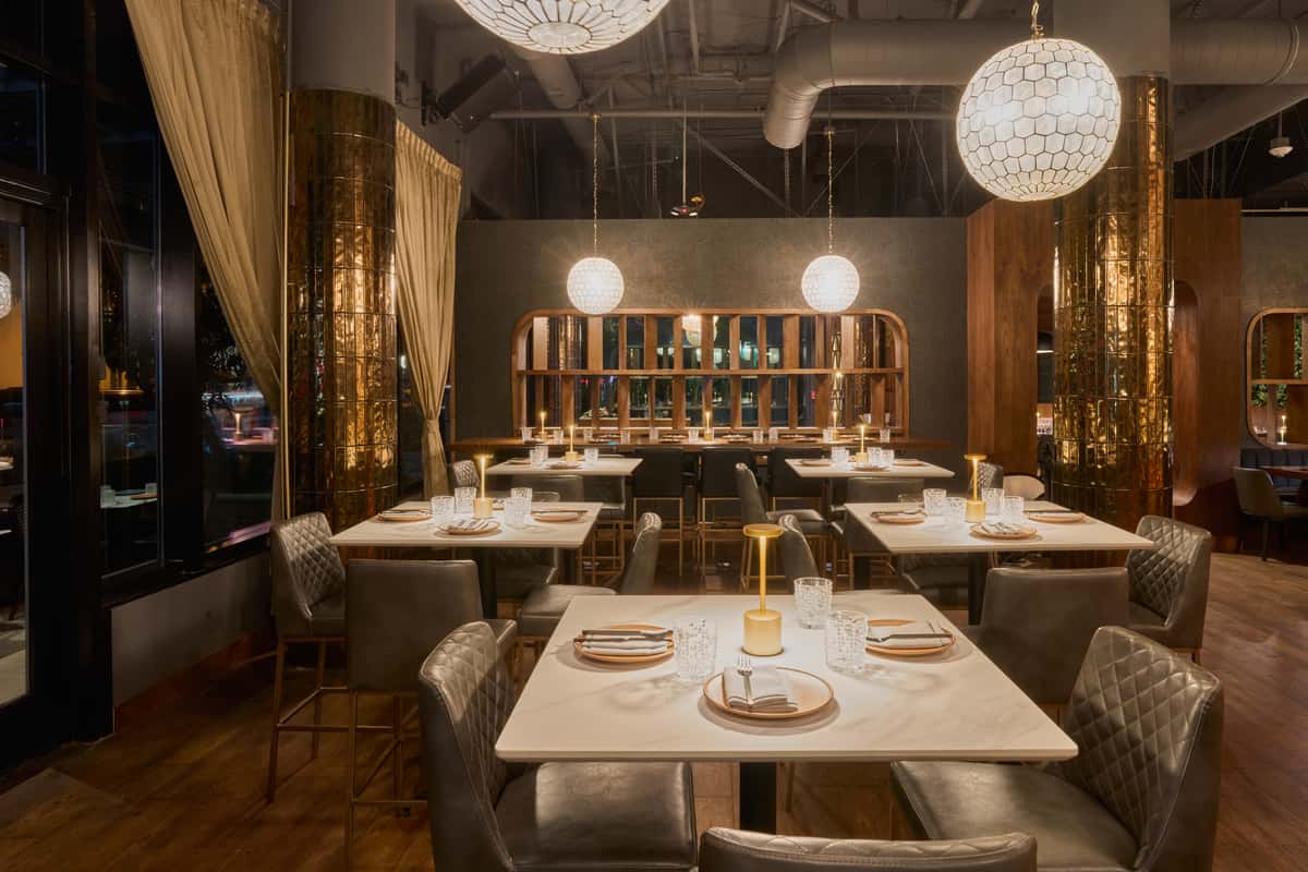 A stylish private event space in Santa Monica, featuring elegant tables set with glassware and modern decor, illuminated by unique pendant lights, perfect for intimate gatherings.