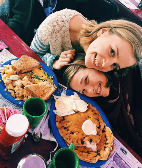 two girls posing for a picture at a table eating breakfast