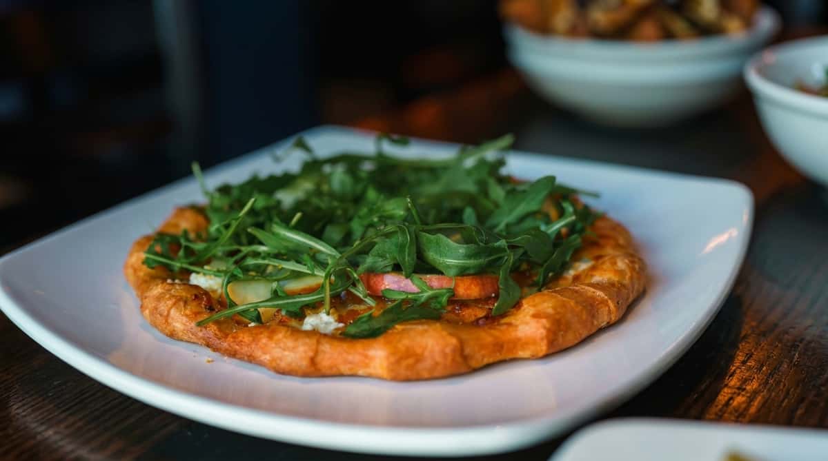 Wood-fired pizza topped with fresh arugula at Oak & Pie in Wichita, KS