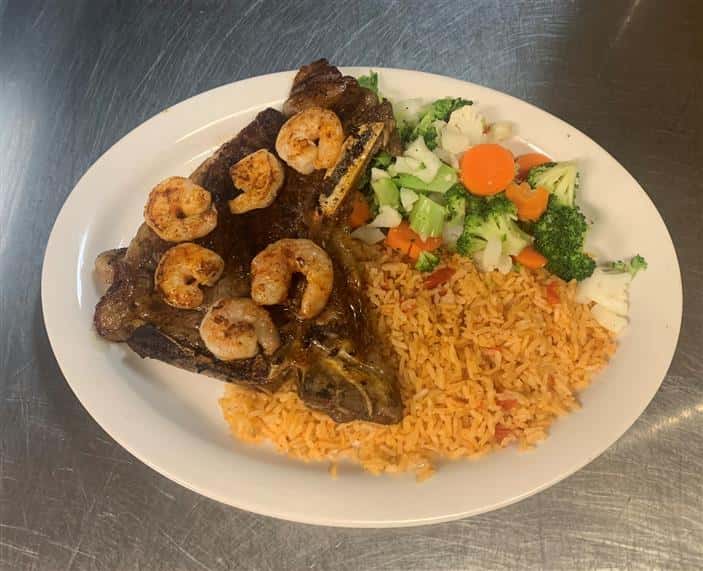 steak topped with shrimp and a side of rice and vegetables