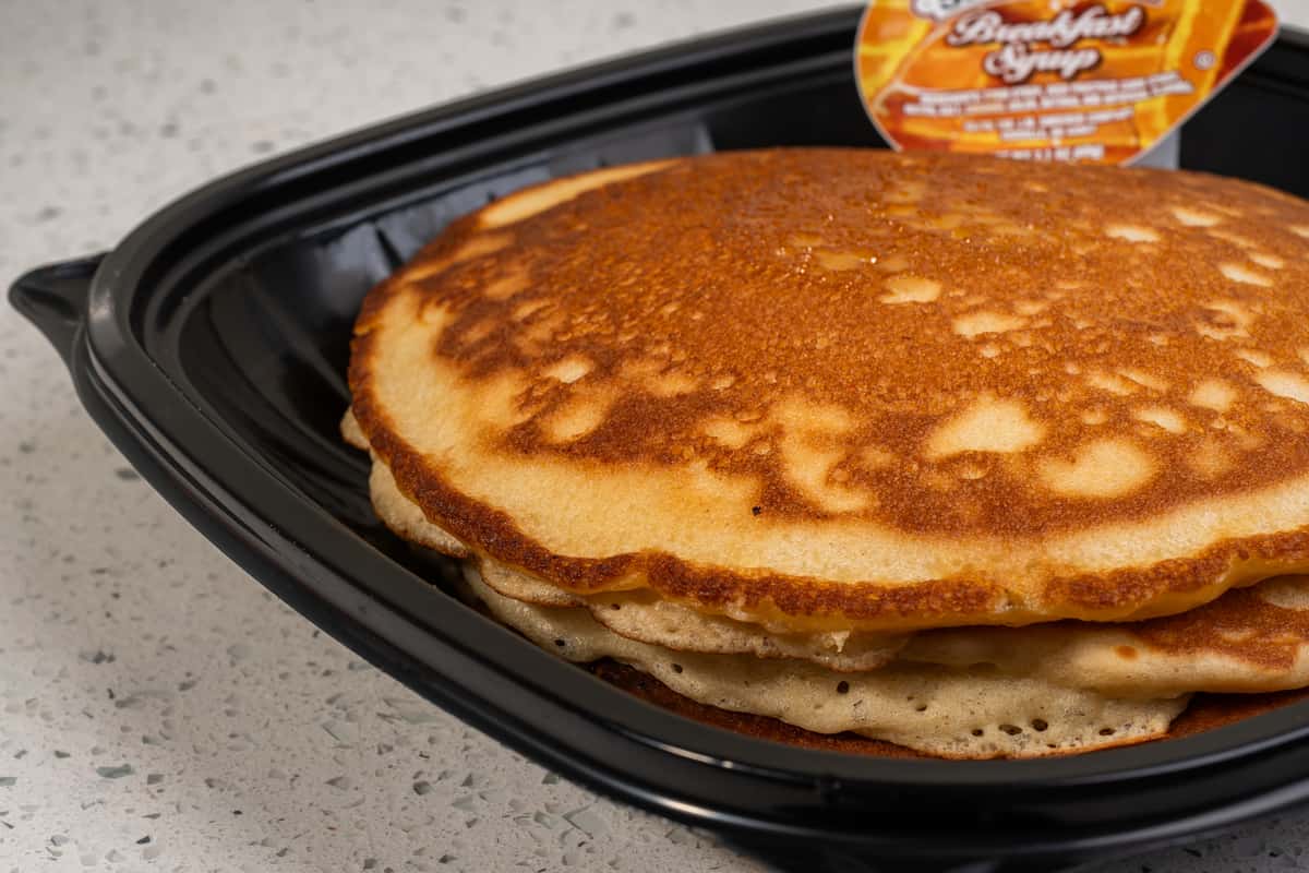 Close-up of a stack of golden sweet cream pancakes with butter on top.