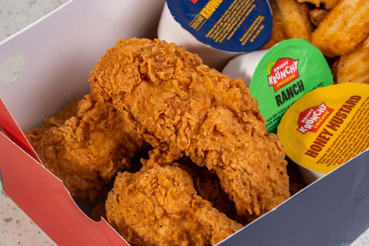 Close-up of crispy chicken tenders with assorted dipping sauces.