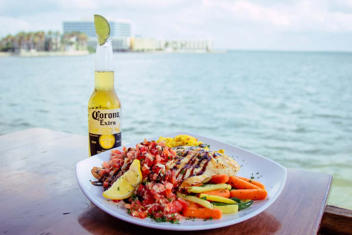 a plate of food and beer by water