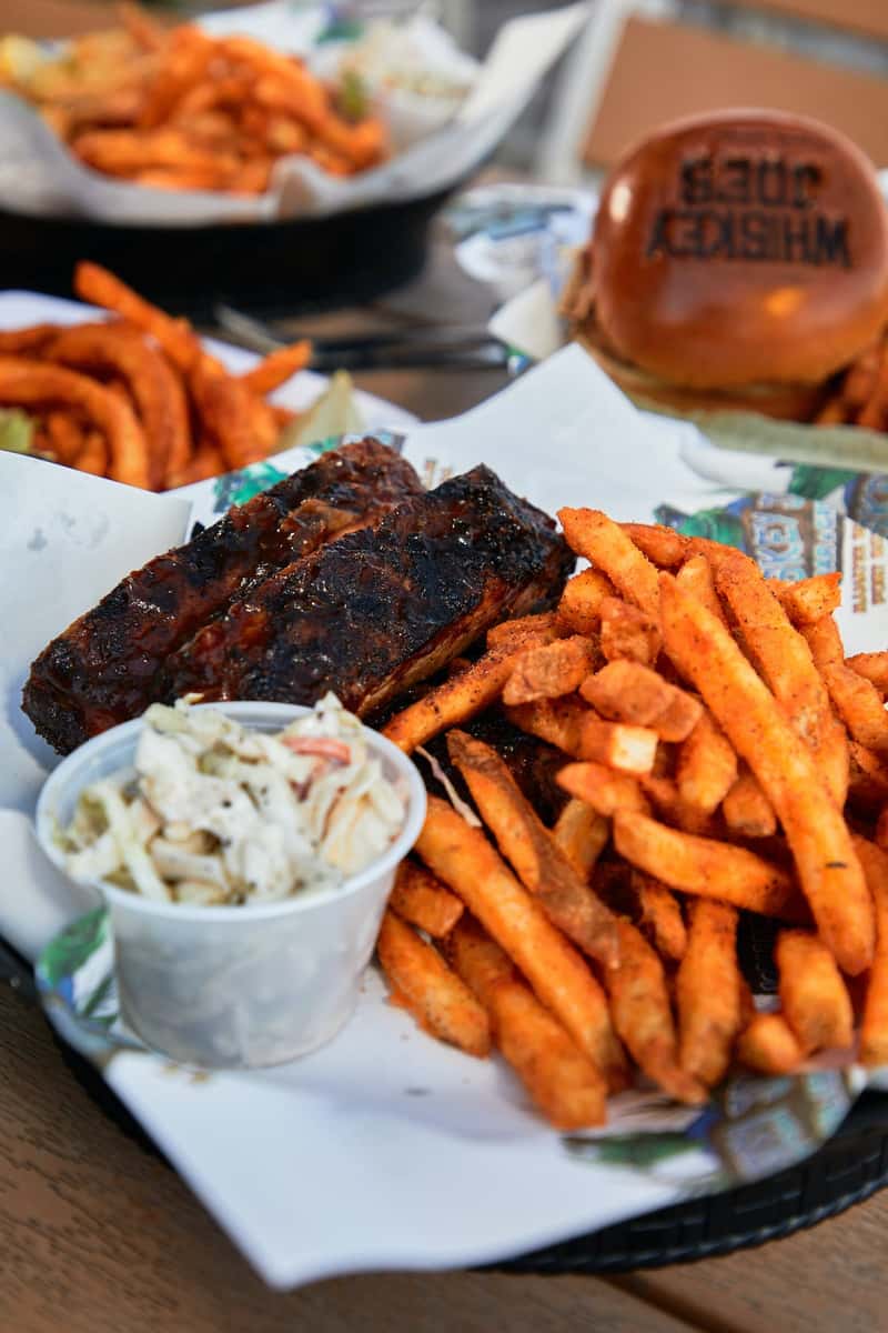 a basket of ribs served with a side of fries and coleslaw