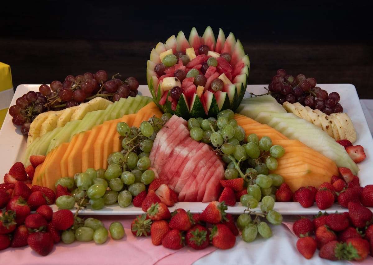 Fresh fruit display platter with watermelon, cantaloupe, honeydew, grapes, and strawberries arranged for an elegant event buffet