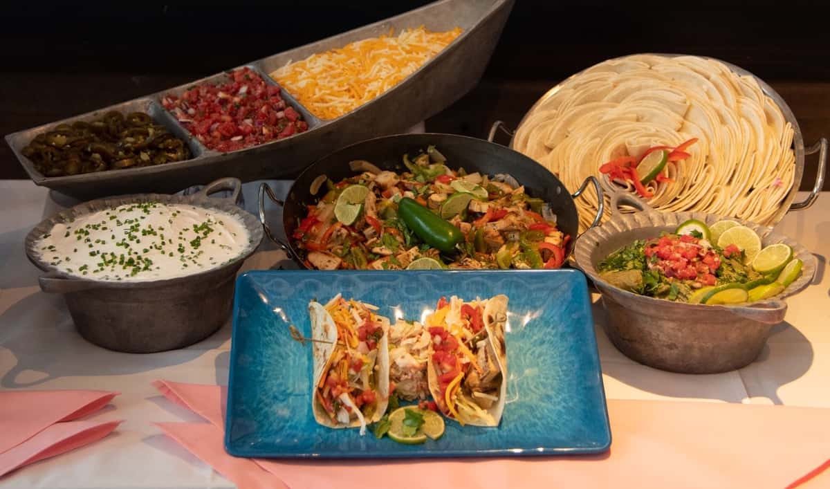a plate of tacos in front of a taco bar
