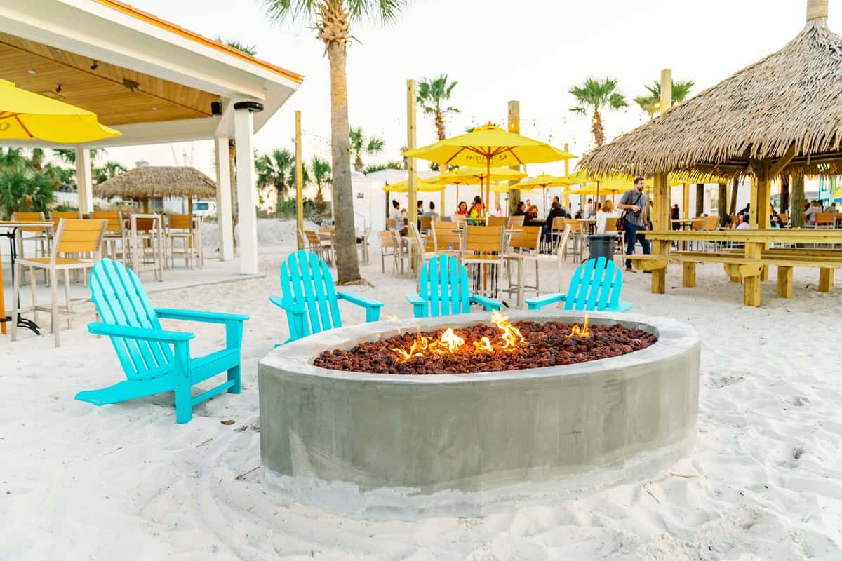 a fire pit and chairs on the beach