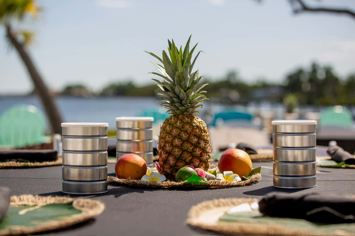 Tropical waterfront table centerpiece with pineapple, citrus, and island-inspired decor for a beach party event