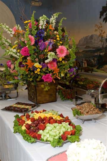 catering table serving a fresh assortment of fruit decorated with a pot of flowers
