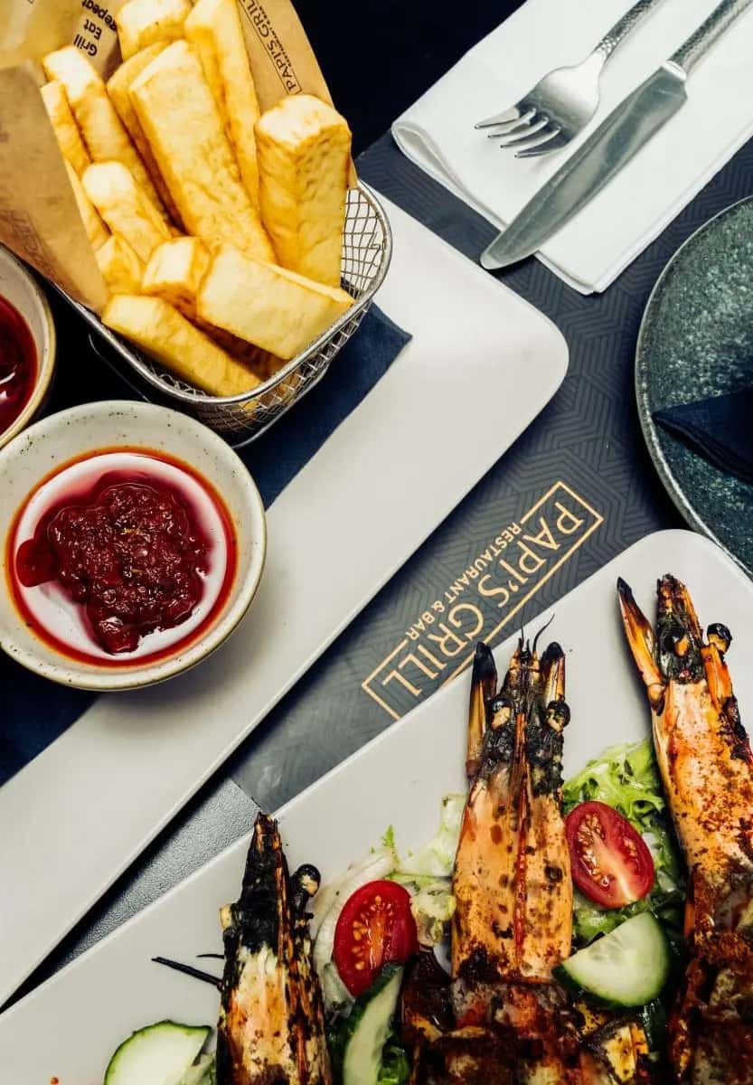 Colorful restaurant spread featuring grilled skewers, crispy fries, and dipping sauces on a modern dining table
