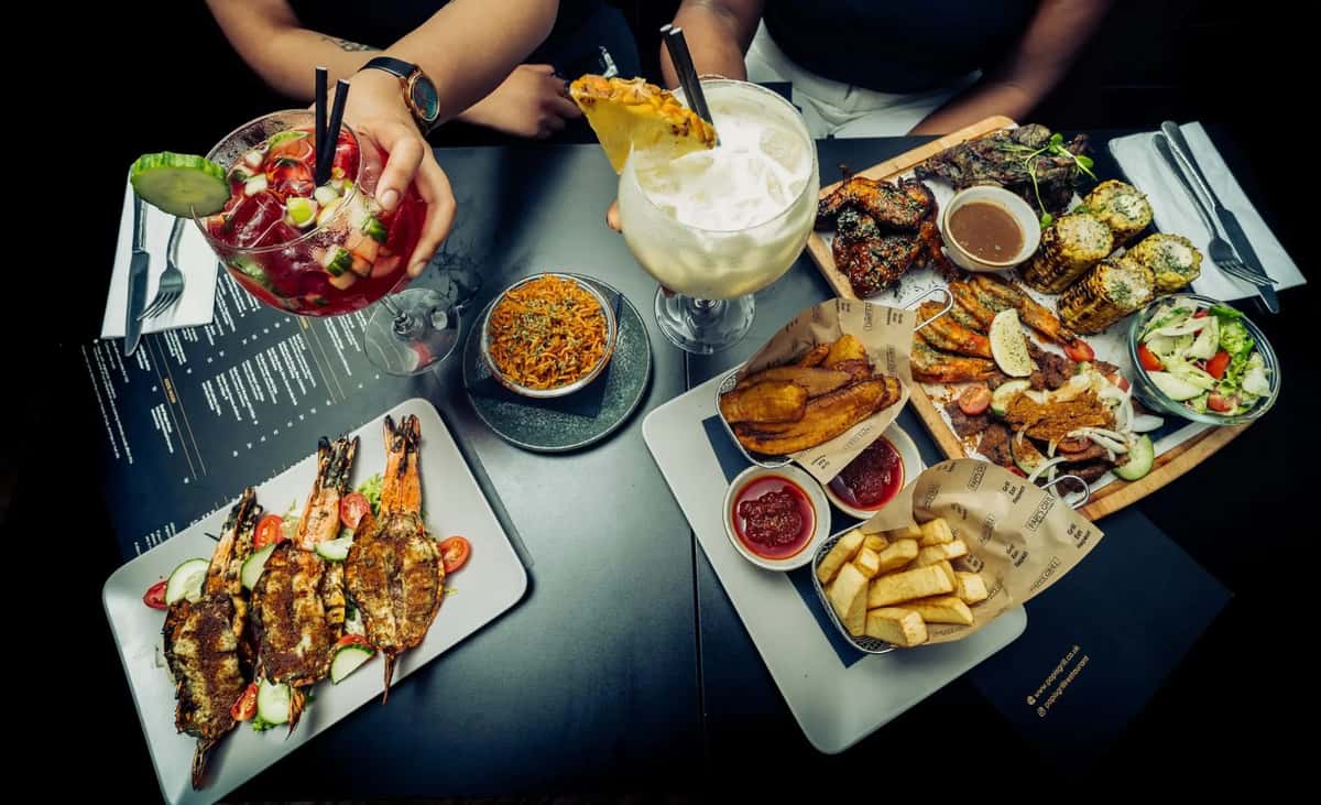 assorted restaurant appetizers and cocktails spread across a table in a vibrant social dining setting