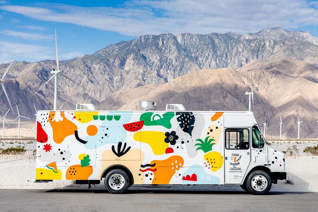 A colorful F10 food truck catering for private events, parked in Palm Springs with picturesque mountains in the background.
