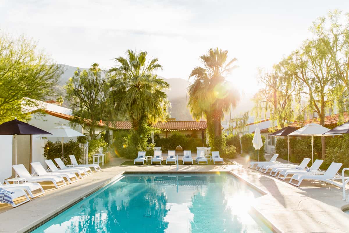 Sunny poolside view with loungers and umbrellas capturing the relaxed vibe of Palm Springs, California at Alcazar