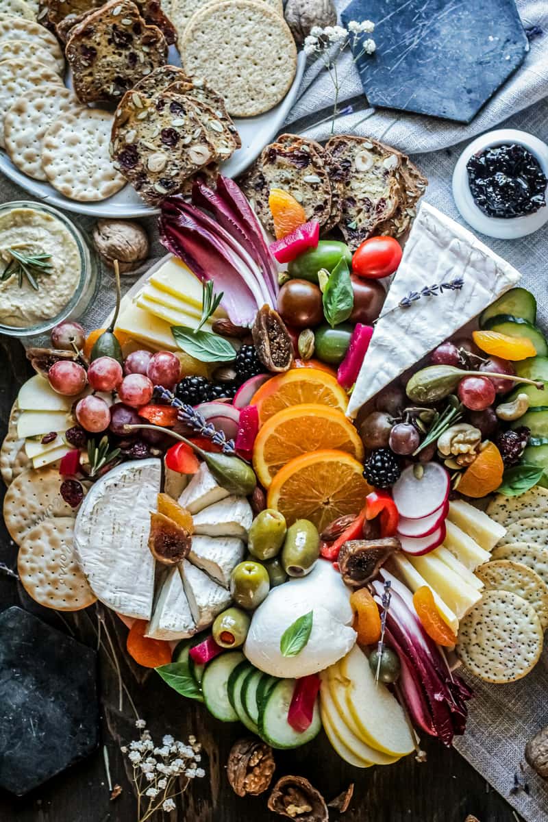 Colorful charcuterie board featuring a variety of cheeses, fresh fruits, olives, sliced vegetables, nuts, crackers, and artisanal bread, perfect for upscale wine bars or rustic grazing table displays.