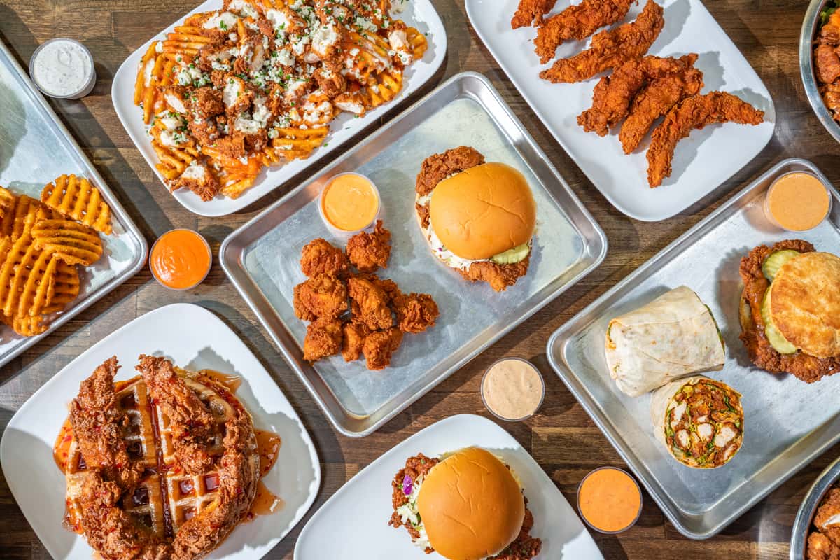A flat lay of a variety of chicken entrees and sides on a wooden table