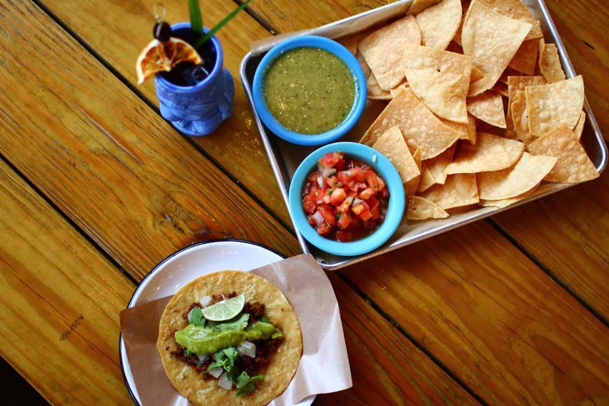 Tacos with guac, salsa, tortilla chips and a tiki cocktail